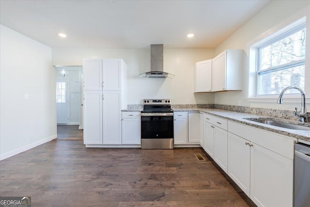 kitchen with a healthy amount of sunlight, wall chimney exhaust hood, stainless steel appliances, and a sink