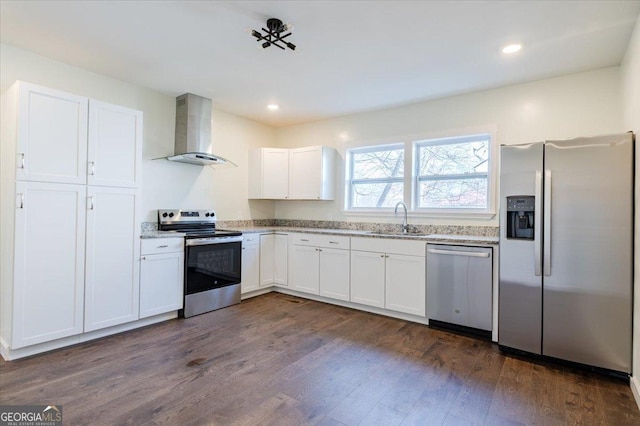 kitchen with a sink, white cabinetry, appliances with stainless steel finishes, wall chimney range hood, and dark wood-style floors