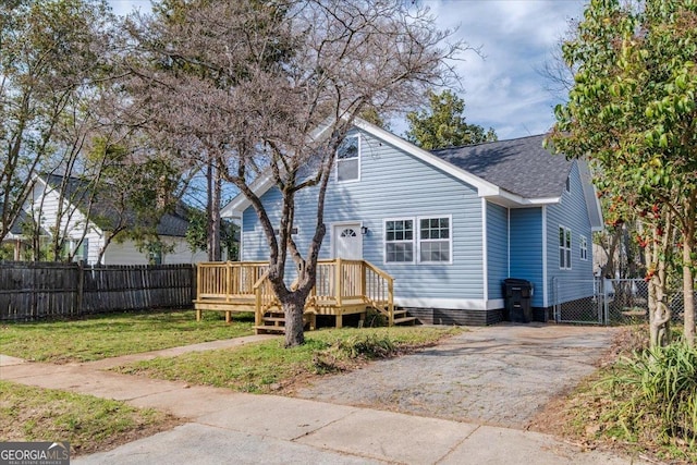 view of front of home with driveway, a shingled roof, a front yard, and fence