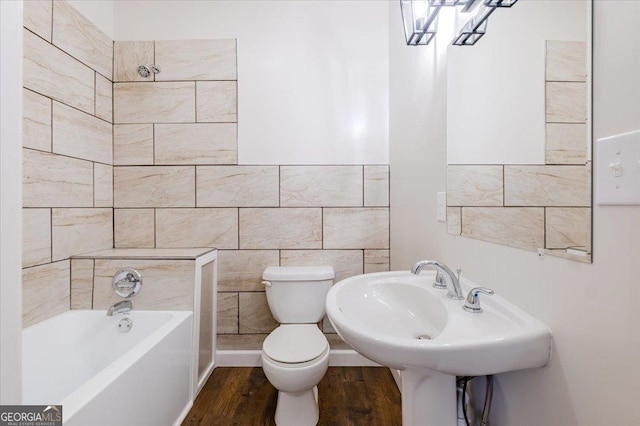 bathroom featuring wood finished floors, tile walls, toilet, and a bathing tub