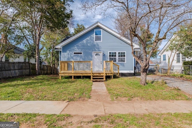 bungalow-style home featuring a fenced backyard, a wooden deck, and a front yard