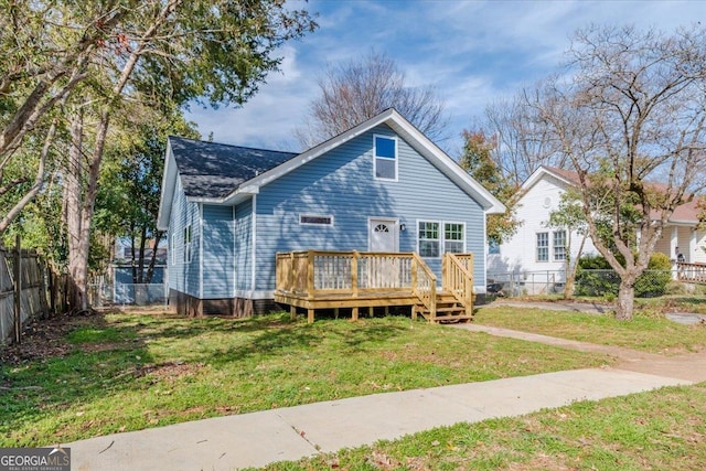 back of property featuring a deck, a shingled roof, a lawn, and a fenced backyard