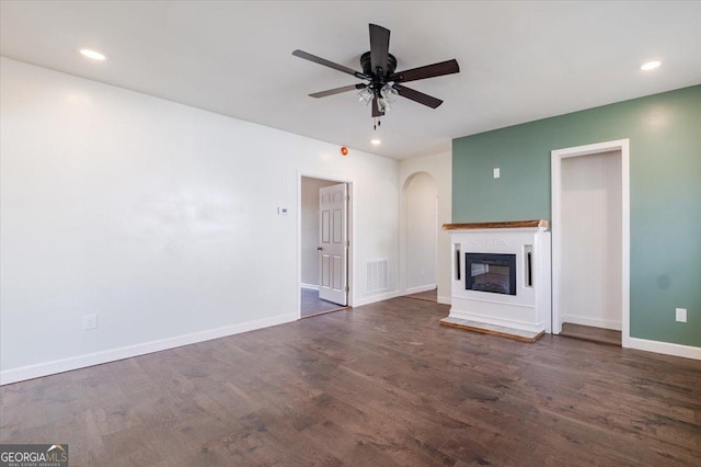 unfurnished living room with a ceiling fan, dark wood-style flooring, visible vents, and baseboards