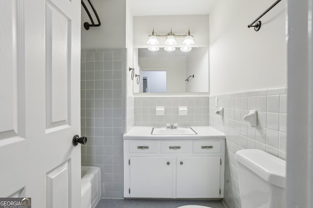 full bath with toilet, a wainscoted wall, bathtub / shower combination, vanity, and tile walls