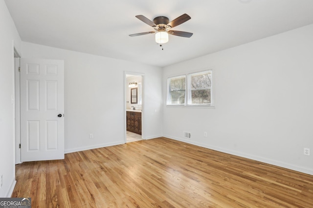 unfurnished bedroom with baseboards, connected bathroom, visible vents, and light wood-style floors