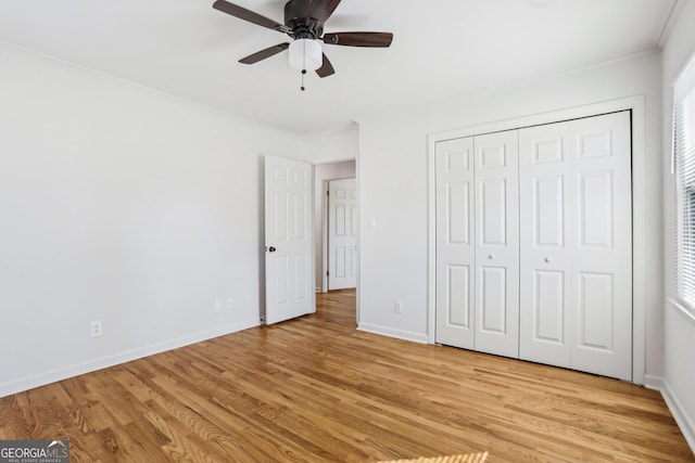 unfurnished bedroom featuring light wood-style floors, a ceiling fan, baseboards, and crown molding