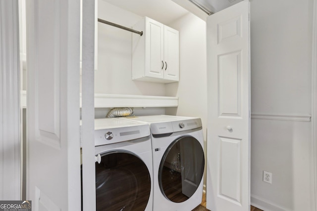 clothes washing area featuring washing machine and clothes dryer and cabinet space