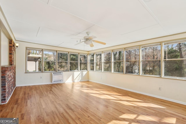 unfurnished sunroom featuring heating unit and a ceiling fan