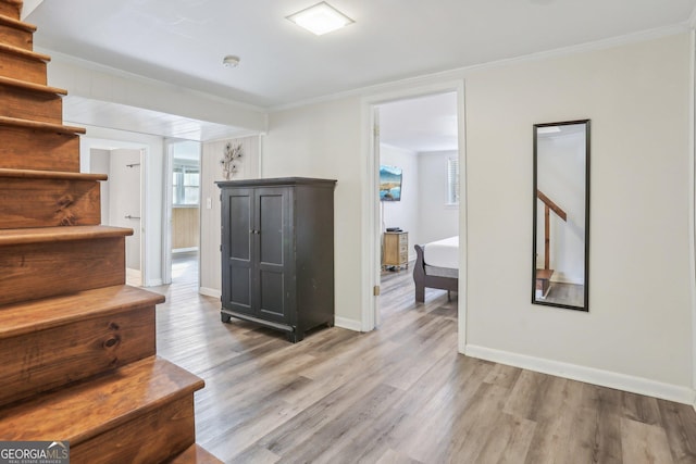 interior space featuring stairs, baseboards, crown molding, and wood finished floors