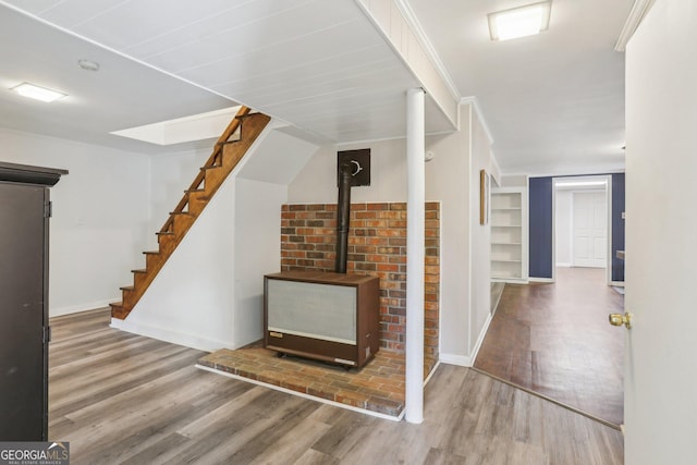 interior space with wood finished floors, a wood stove, and baseboards