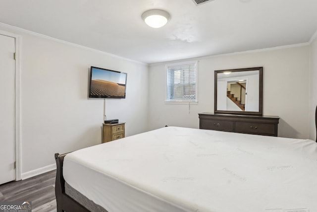 bedroom featuring dark wood-style floors, baseboards, visible vents, and ornamental molding