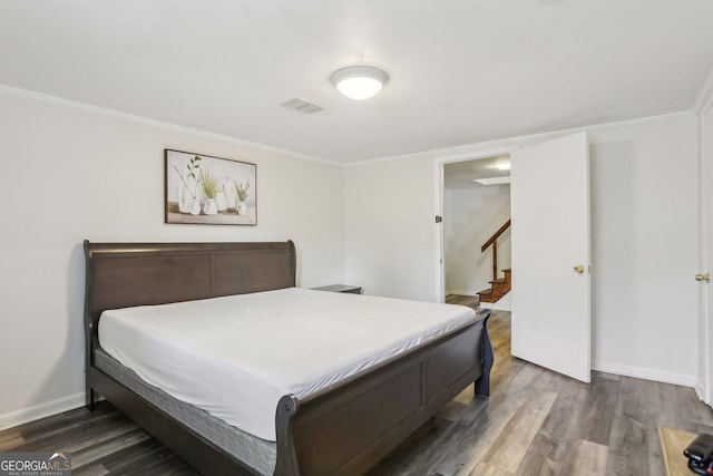 bedroom featuring ornamental molding, wood finished floors, visible vents, and baseboards