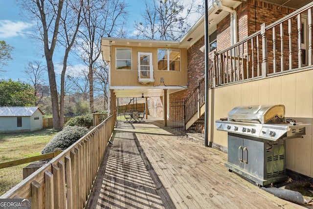 wooden terrace featuring stairs, grilling area, and an outdoor structure