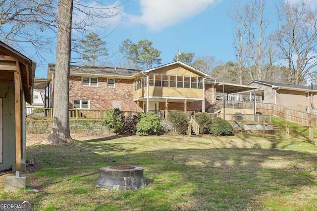 rear view of property with an outdoor fire pit, brick siding, fence, stairs, and a yard