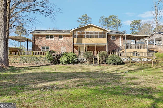 rear view of house featuring a yard, brick siding, a wooden deck, and fence