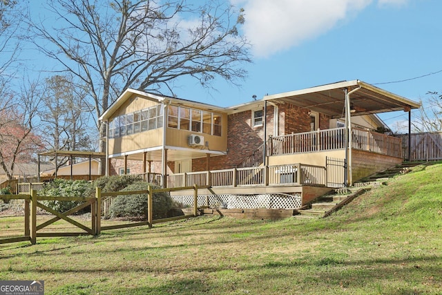 rear view of house with brick siding, a yard, a deck, and fence