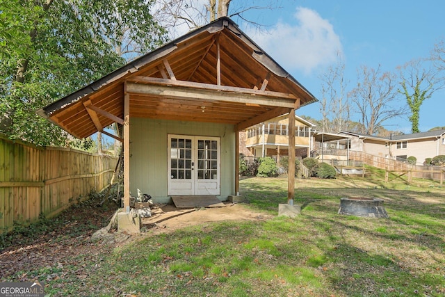 rear view of property with a fenced backyard, an outdoor structure, french doors, and a yard