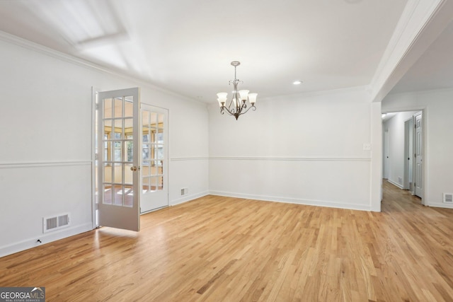 unfurnished dining area with light wood finished floors, visible vents, an inviting chandelier, ornamental molding, and baseboards