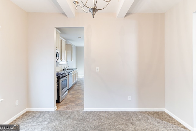 kitchen with appliances with stainless steel finishes, light carpet, a sink, and beamed ceiling