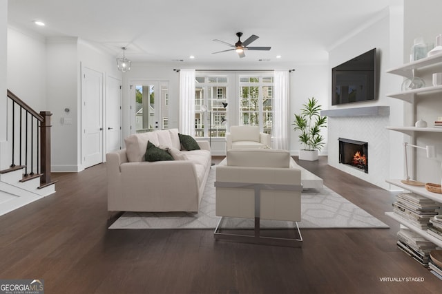 living area featuring a tile fireplace, recessed lighting, wood finished floors, stairs, and crown molding