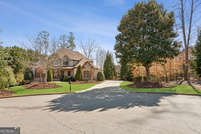 view of front facade with stone siding, concrete driveway, and a front yard