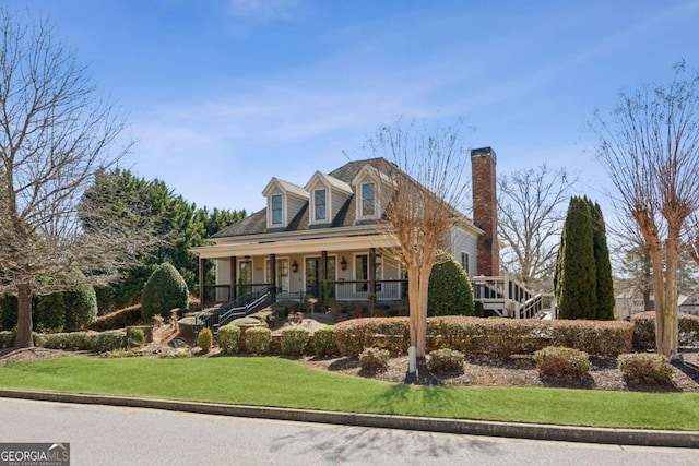 cape cod-style house with a porch, a front yard, and a chimney