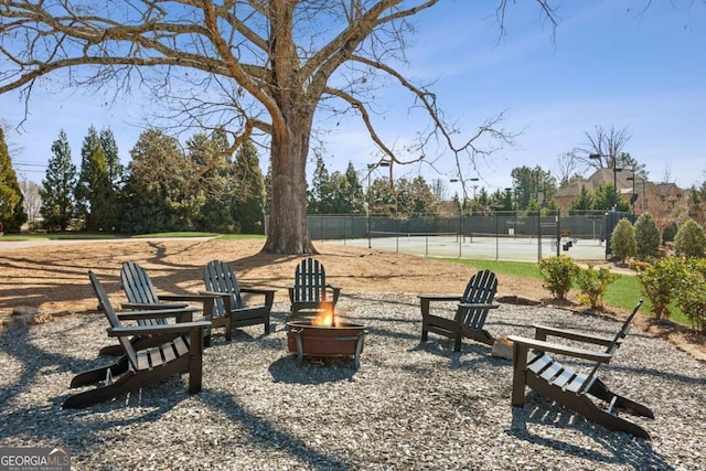 surrounding community with a tennis court, an outdoor fire pit, and fence