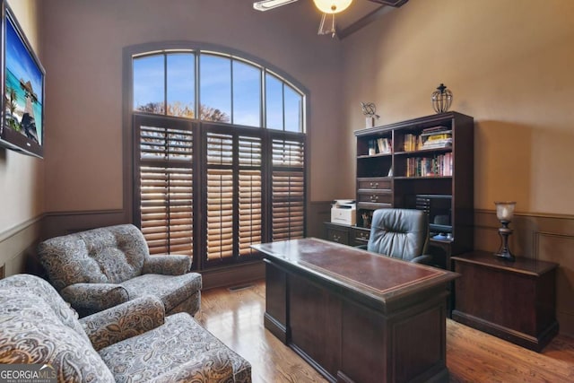 office featuring a wainscoted wall, a ceiling fan, and wood finished floors