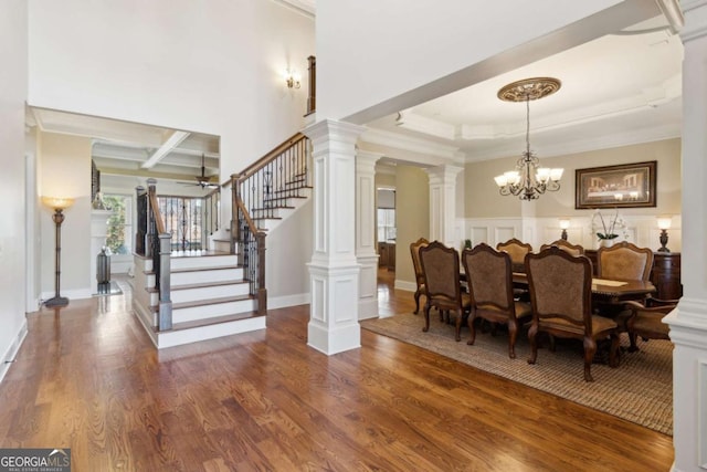 dining area with a notable chandelier, decorative columns, stairway, ornamental molding, and wood finished floors