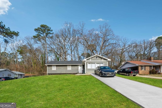 view of front of house with driveway, an attached garage, and a front lawn