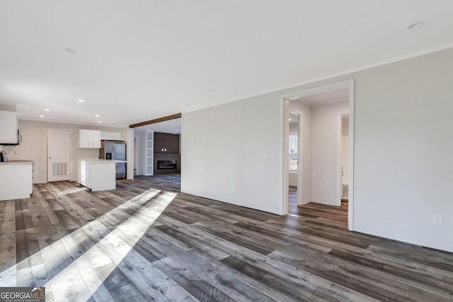 unfurnished living room with visible vents, a glass covered fireplace, wood finished floors, and recessed lighting