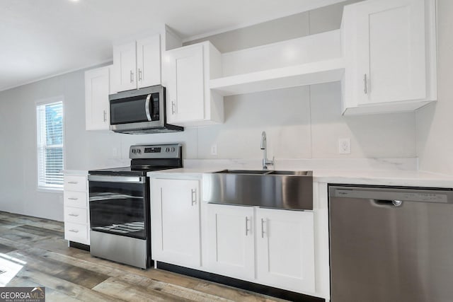 kitchen featuring white cabinets, light wood-style floors, stainless steel appliances, and a sink