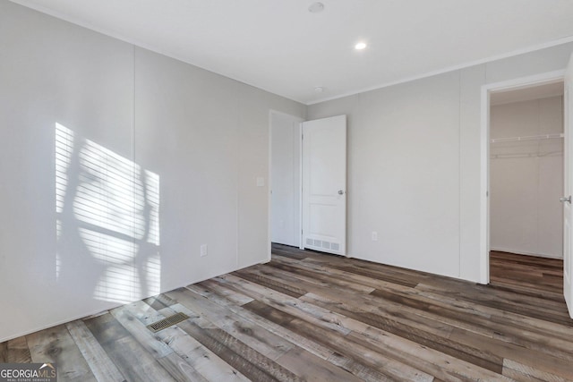 unfurnished bedroom featuring wood finished floors, visible vents, and a walk in closet