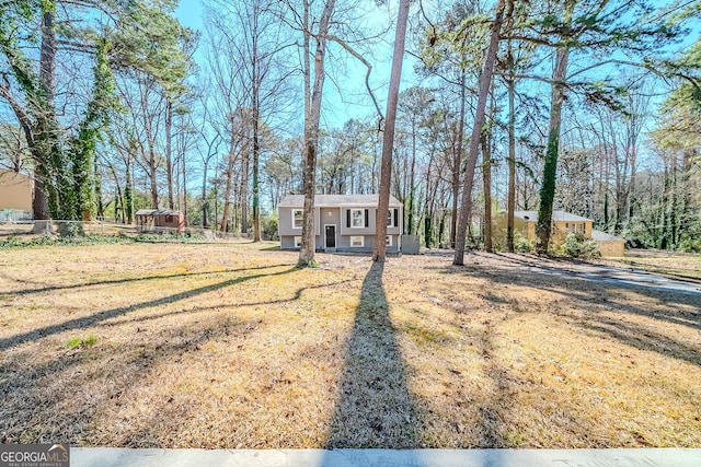 bi-level home with fence, a front lawn, and an outbuilding