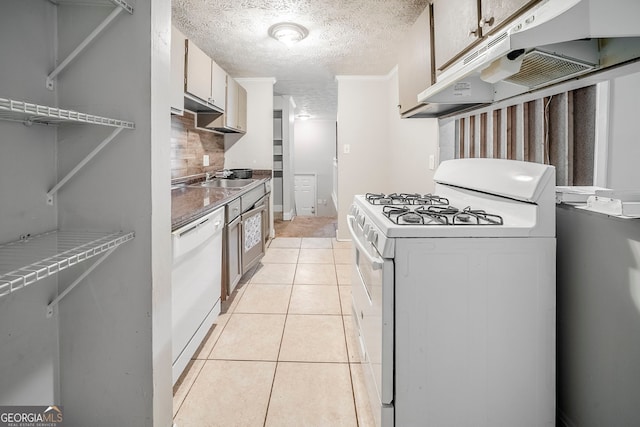 kitchen with white appliances, light tile patterned floors, a textured ceiling, under cabinet range hood, and backsplash