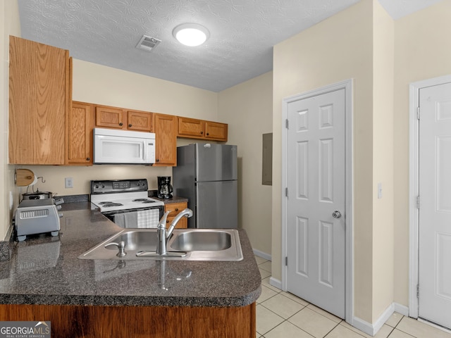 kitchen with white microwave, range with electric cooktop, a sink, visible vents, and freestanding refrigerator