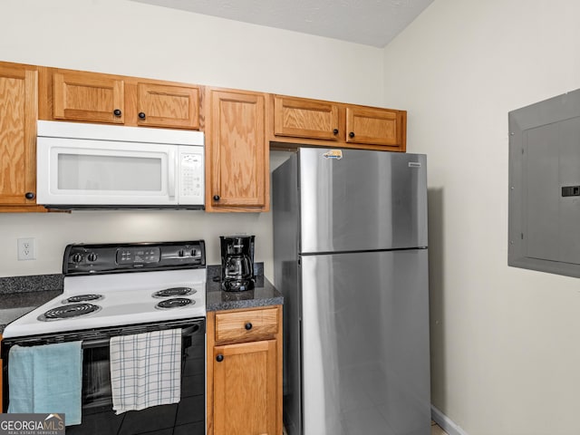 kitchen with dark countertops, white microwave, freestanding refrigerator, range with electric cooktop, and electric panel