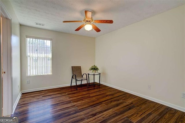 empty room with baseboards, a textured ceiling, visible vents, and wood finished floors