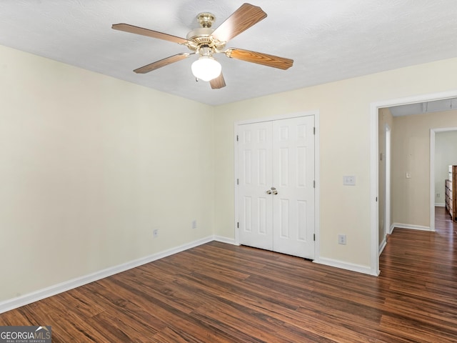 unfurnished bedroom featuring a ceiling fan, a closet, dark wood finished floors, and baseboards