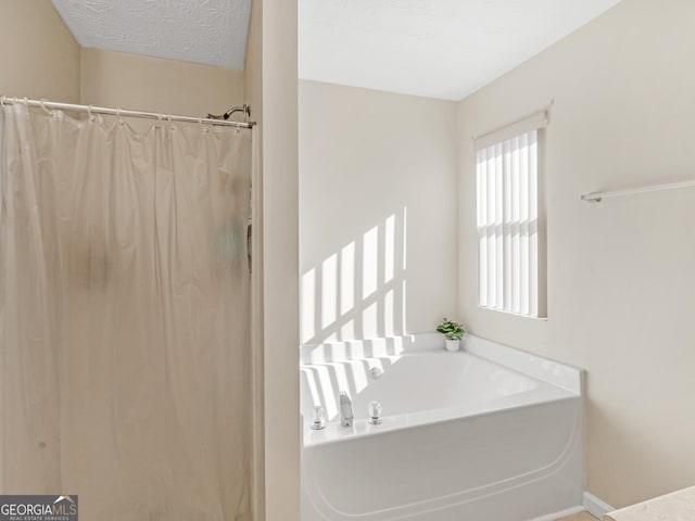 bathroom with a textured ceiling, a bath, and a shower with curtain