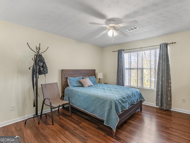 bedroom featuring visible vents, a textured ceiling, baseboards, and wood finished floors