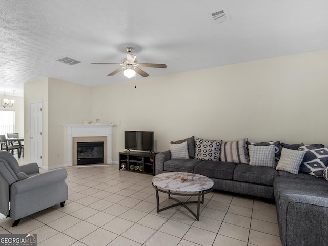 living area featuring ceiling fan with notable chandelier, visible vents, and light tile patterned floors