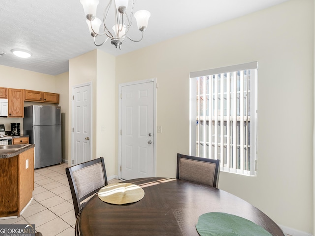 dining area featuring a textured ceiling, a notable chandelier, and light tile patterned flooring