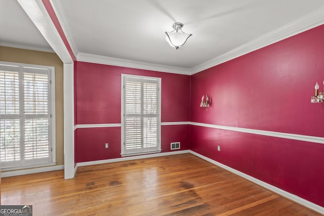 unfurnished room with ornamental molding, visible vents, baseboards, and wood finished floors