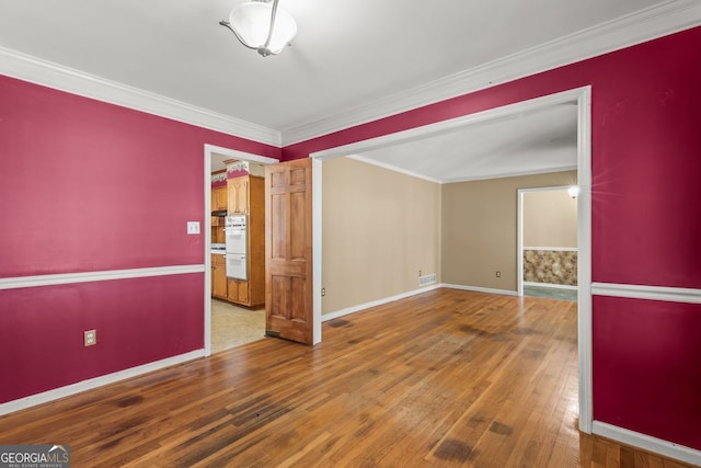 unfurnished room featuring ornamental molding, visible vents, baseboards, and hardwood / wood-style flooring