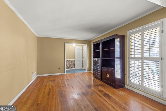 spare room with baseboards, visible vents, ornamental molding, and hardwood / wood-style floors