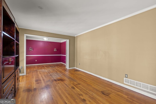 unfurnished living room featuring visible vents, crown molding, baseboards, and hardwood / wood-style flooring