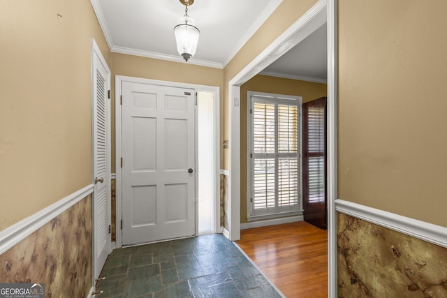 foyer with crown molding, a wainscoted wall, and stone tile floors