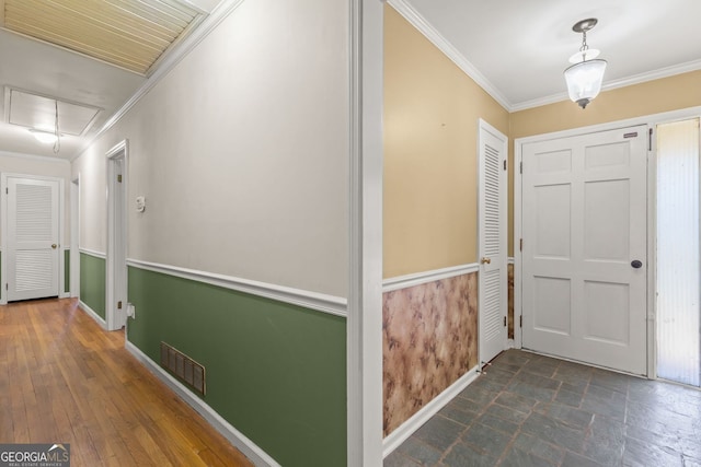 hallway featuring visible vents, attic access, ornamental molding, stone finish floor, and baseboards