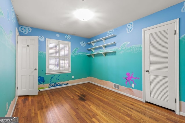 unfurnished bedroom featuring hardwood / wood-style floors, visible vents, and baseboards